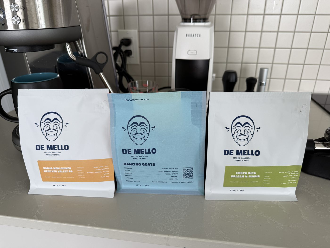 Three De Mello coffee bags on a kitchen counter