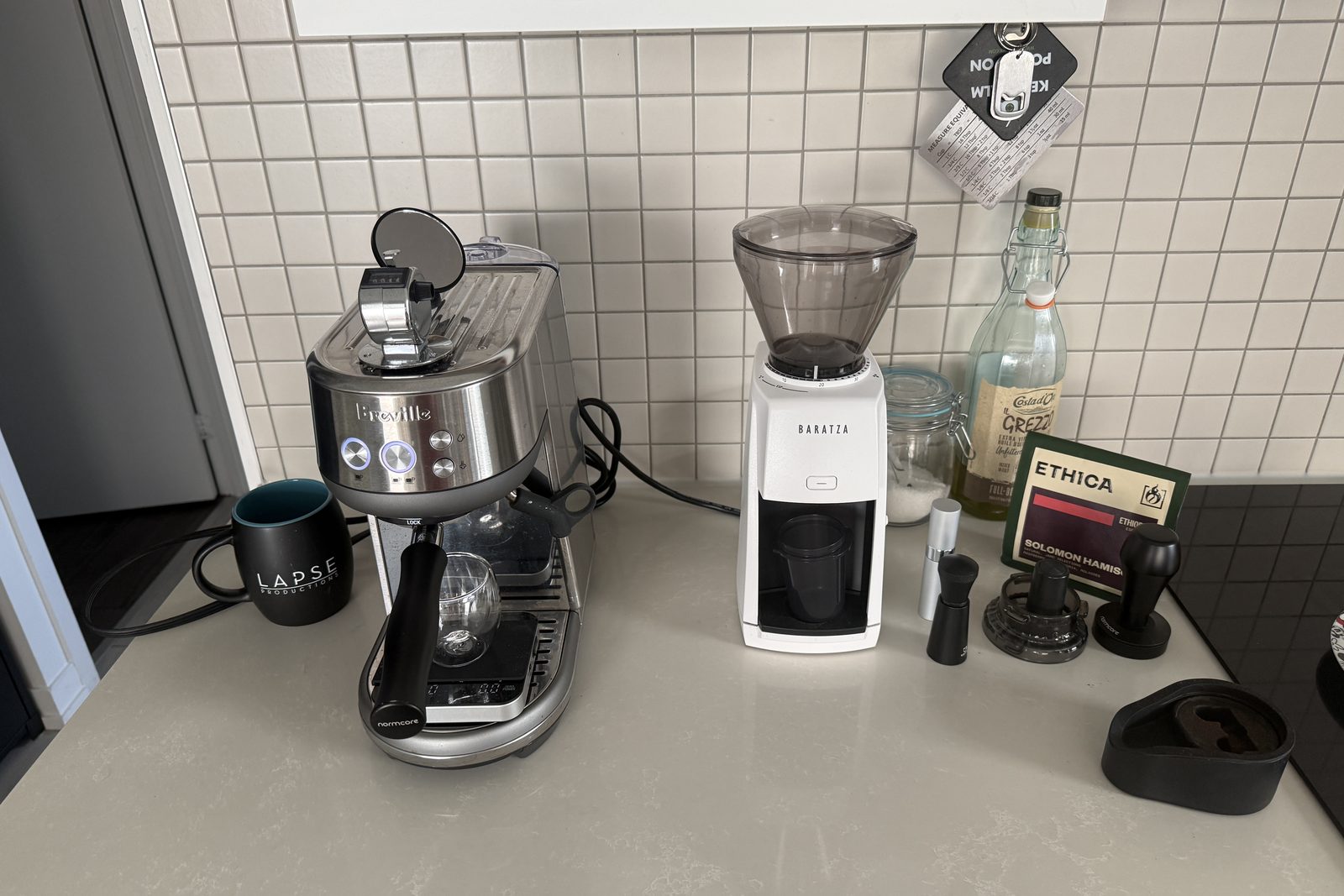 Breville Bambino espresso machine and white Baratza Encore ESP grinder on a kitchen counter