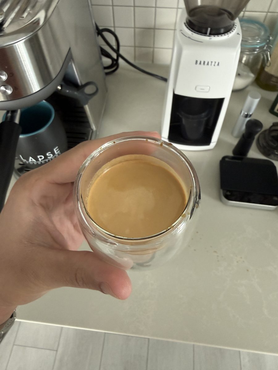 An espresso shot with crema in a double walled glass