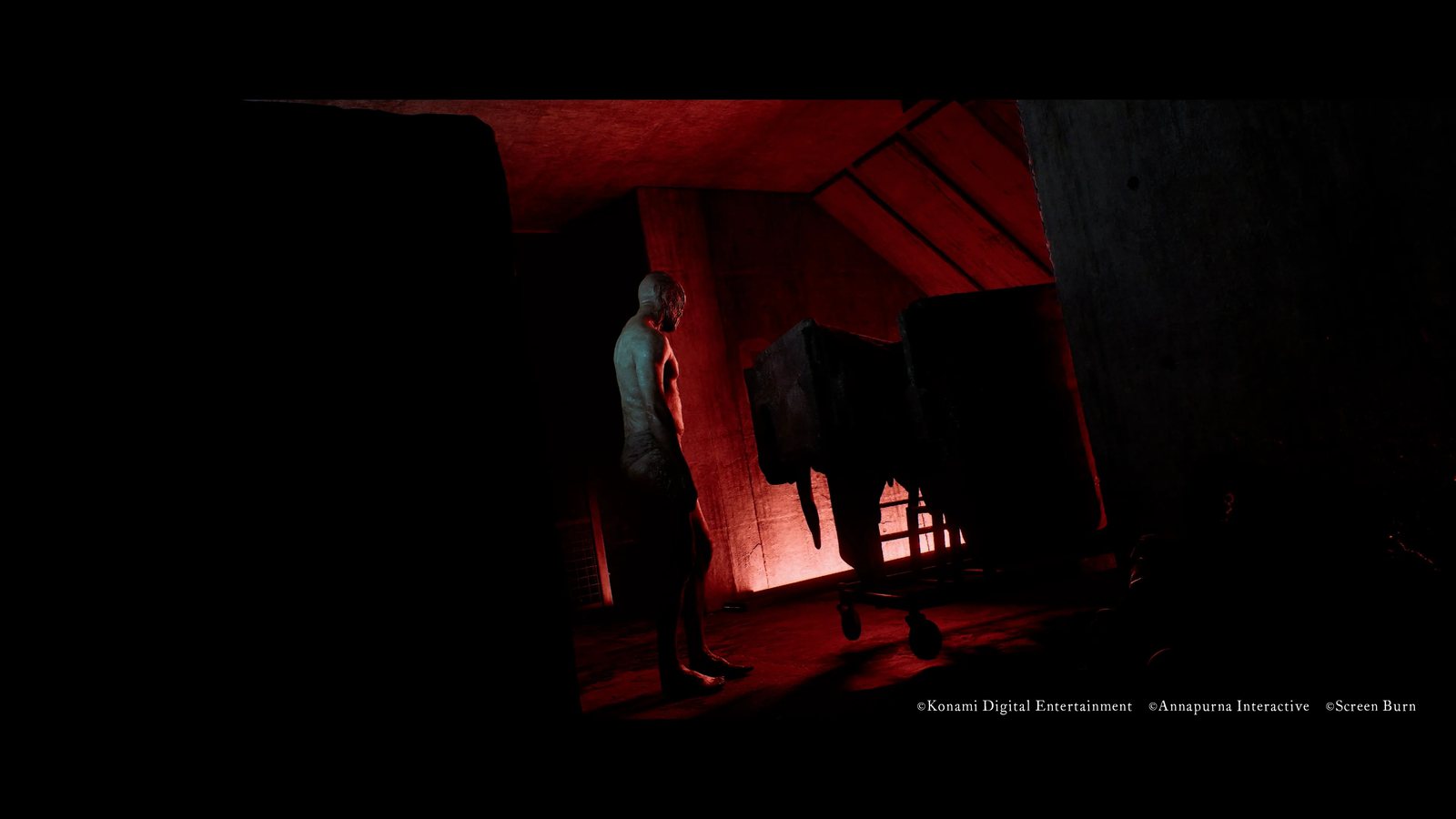 An enemy stands beside a trolley in a dark room lit by red light